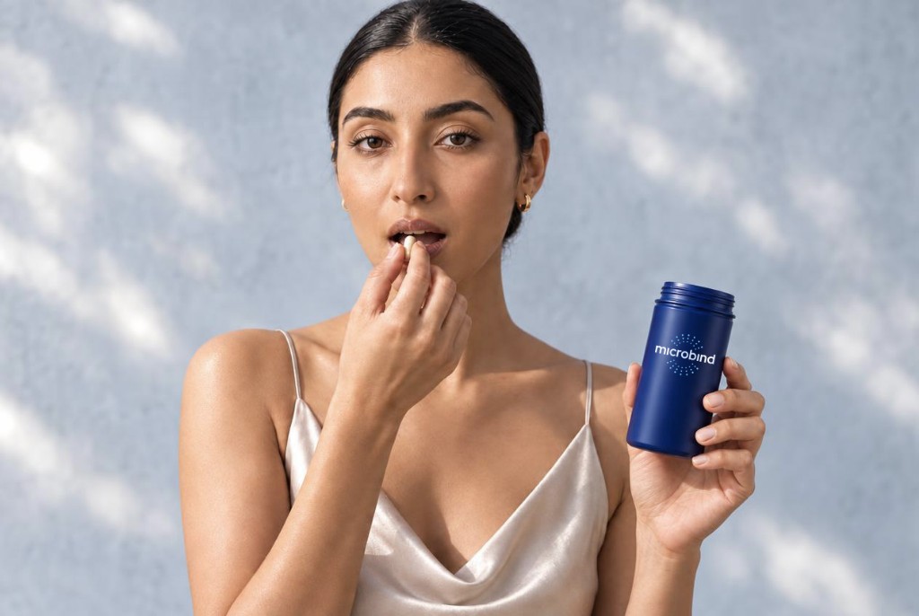 Woman taking a microBIND capsule while holding the MB01™ bottle